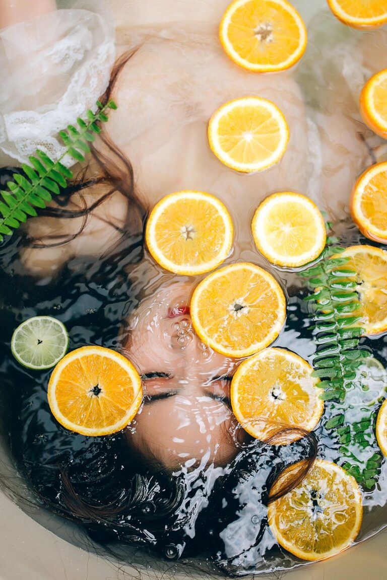 Orangen- und Limettenscheiben schwimmen auf Wasser mit Farnblättern.