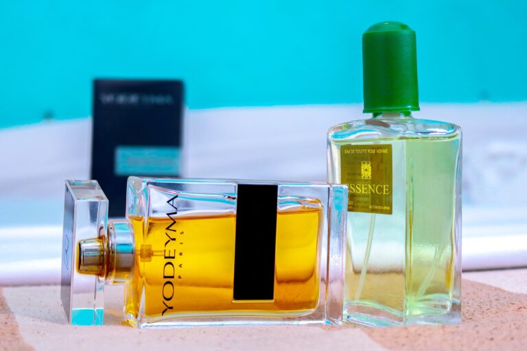 Zwei Parfumflaschen auf einer Oberfläche vor blauem Hintergrund.