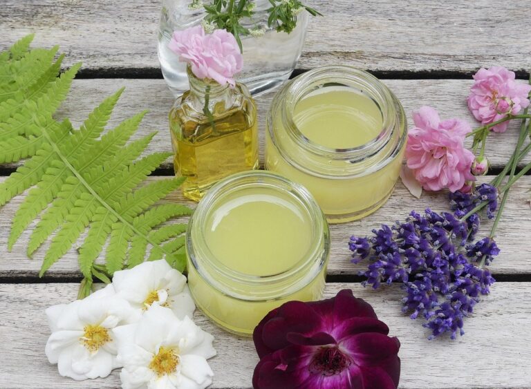 Glasgefäße mit gelbem Inhalt, umgeben von Blumen und Farnen auf hellem Holz.