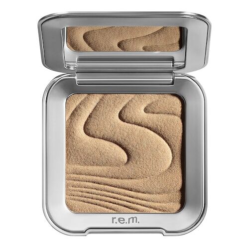 Silberne Lidschattenverpackung mit sandfarbenem Pudermuster im Inneren.