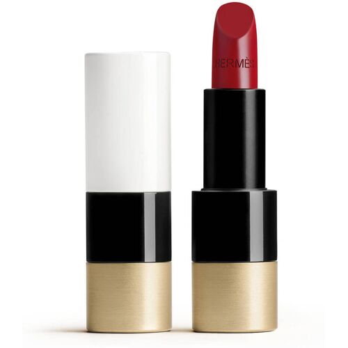 Roter Hermès-Lippenstift mit goldener und schwarzer Hülse neben geöffneter Kappe. Roter Hermès-Lippenstift mit goldener und schwarzer Hülse neben geöffneter Kappe.