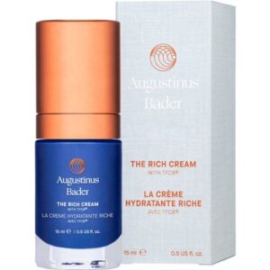 Blaue Flasche und Verpackung von Augustinus Bader The Rich Cream vor weißem Hintergrund.