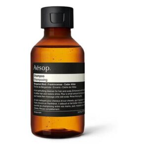Braune Plastikflasche mit schwarzem Deckel und weißem Etikett mit Aufschrift "Aesop Shampoo"